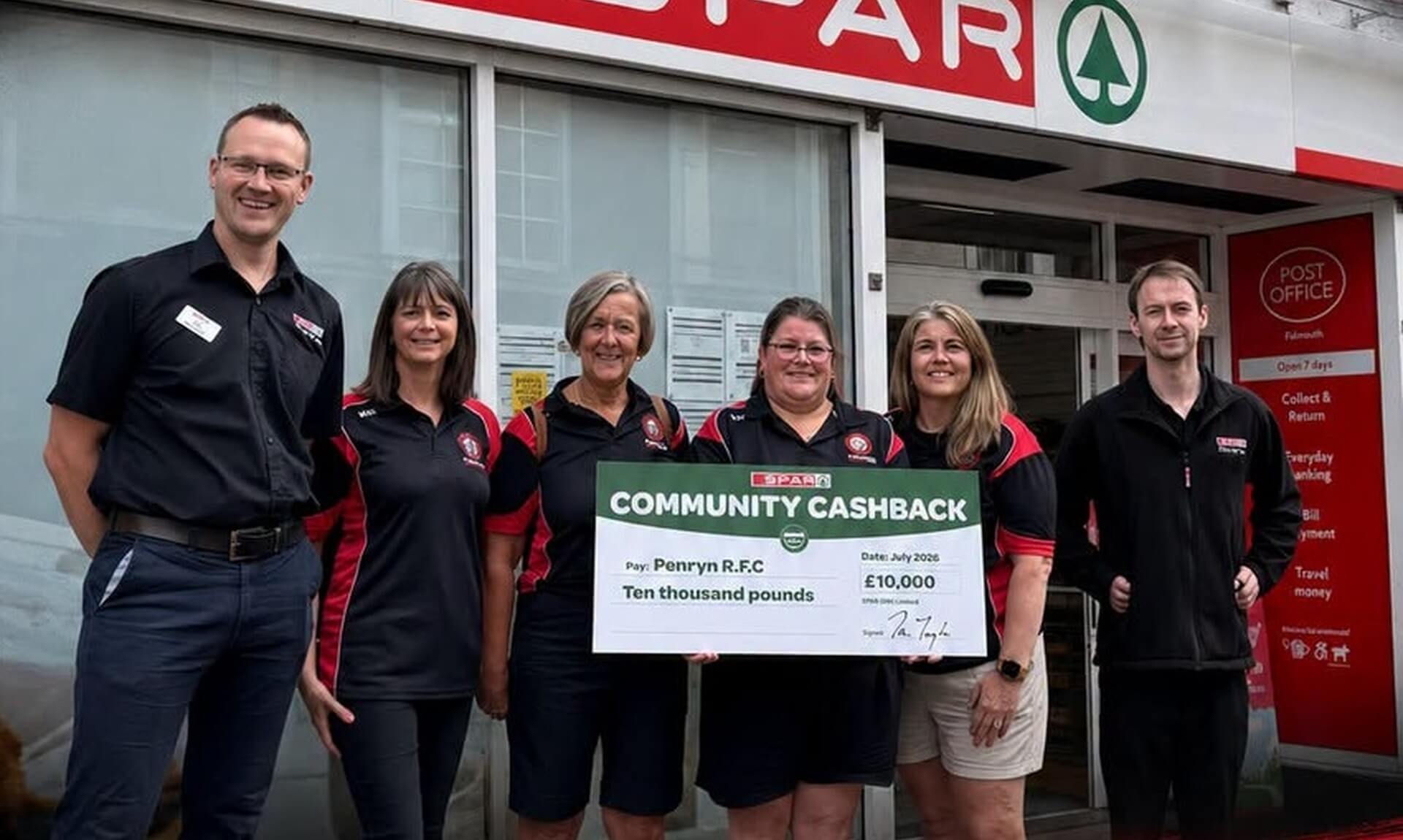 Penryn RFC members and SPAR staff hold a giant £10,000 Community Cashback cheque outside a SPAR store