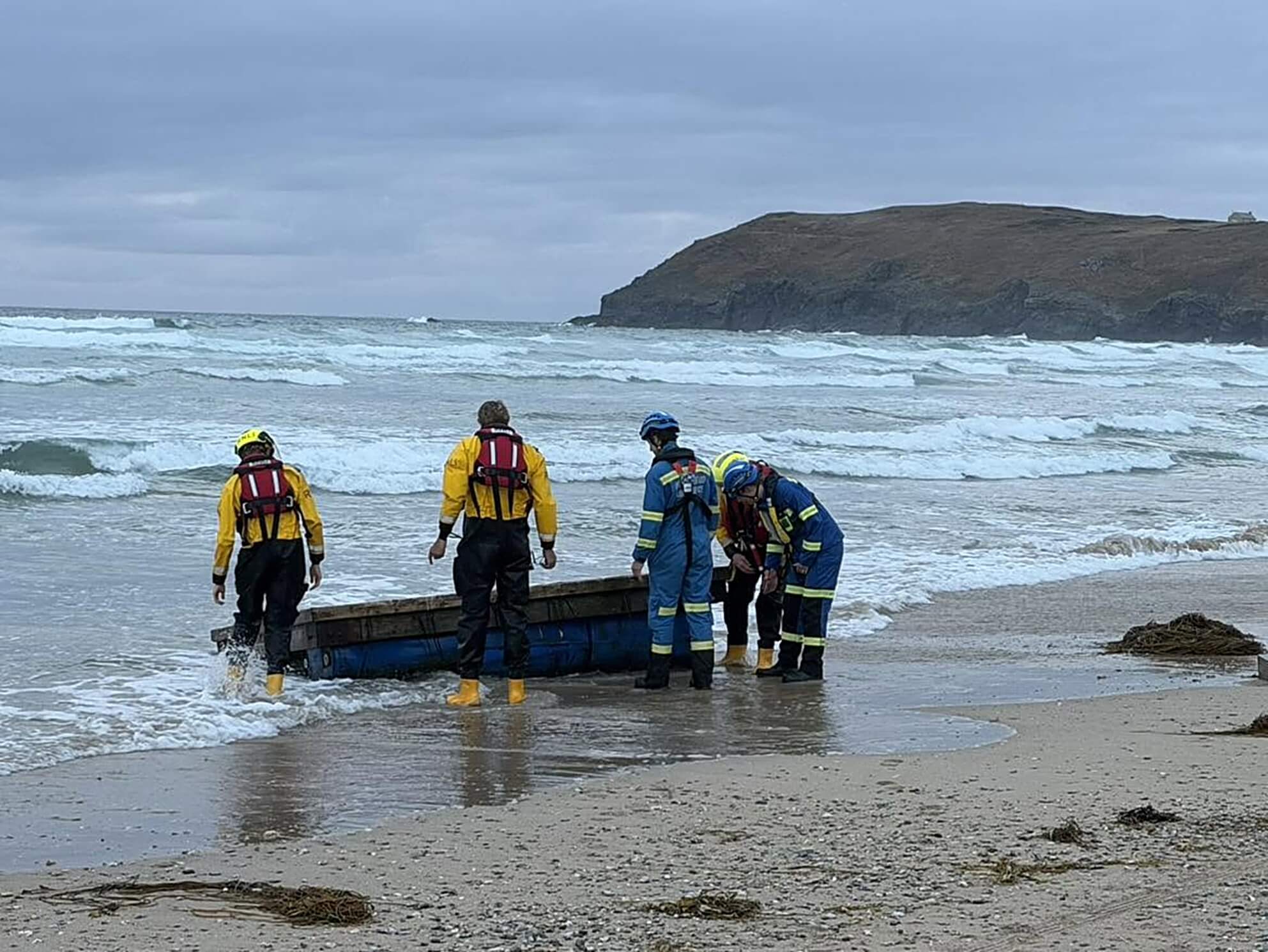 RNLI and coastguard crews dragging the platform up the beach at Perranporth