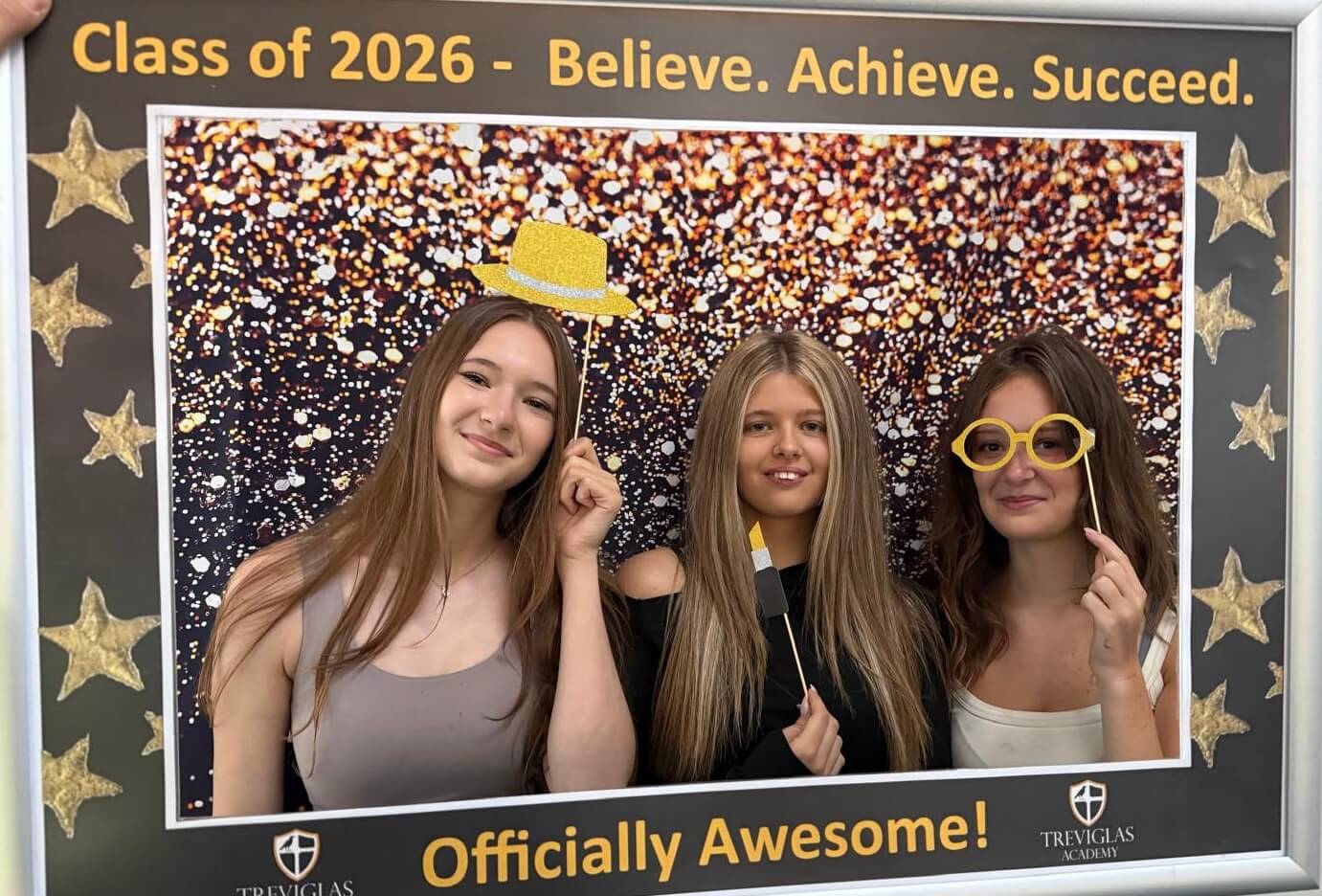 Three Treviglas Academy students posing in the Class of 2026 photo frame