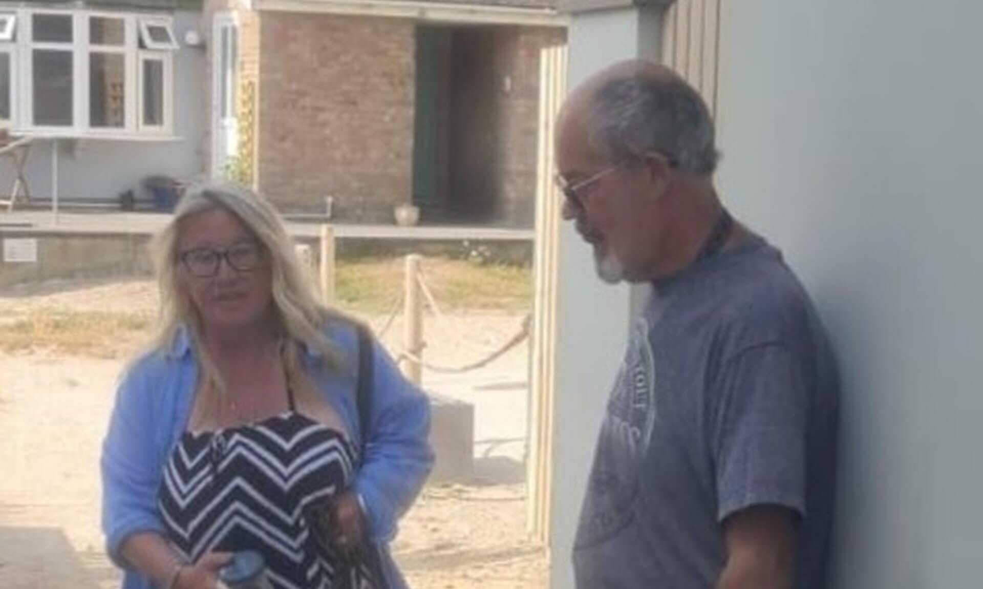A man and a woman standing with two dogs outside a building