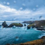 Rain-specked view over a Cornish cove and cliffs