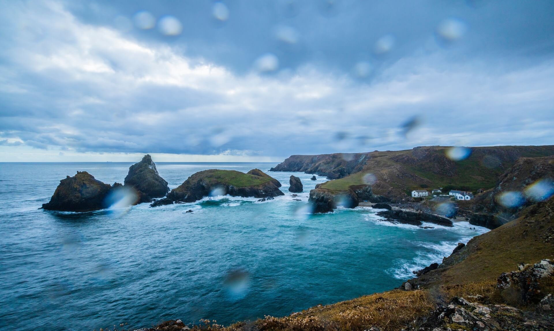 Rain-specked view over a Cornish cove and cliffs