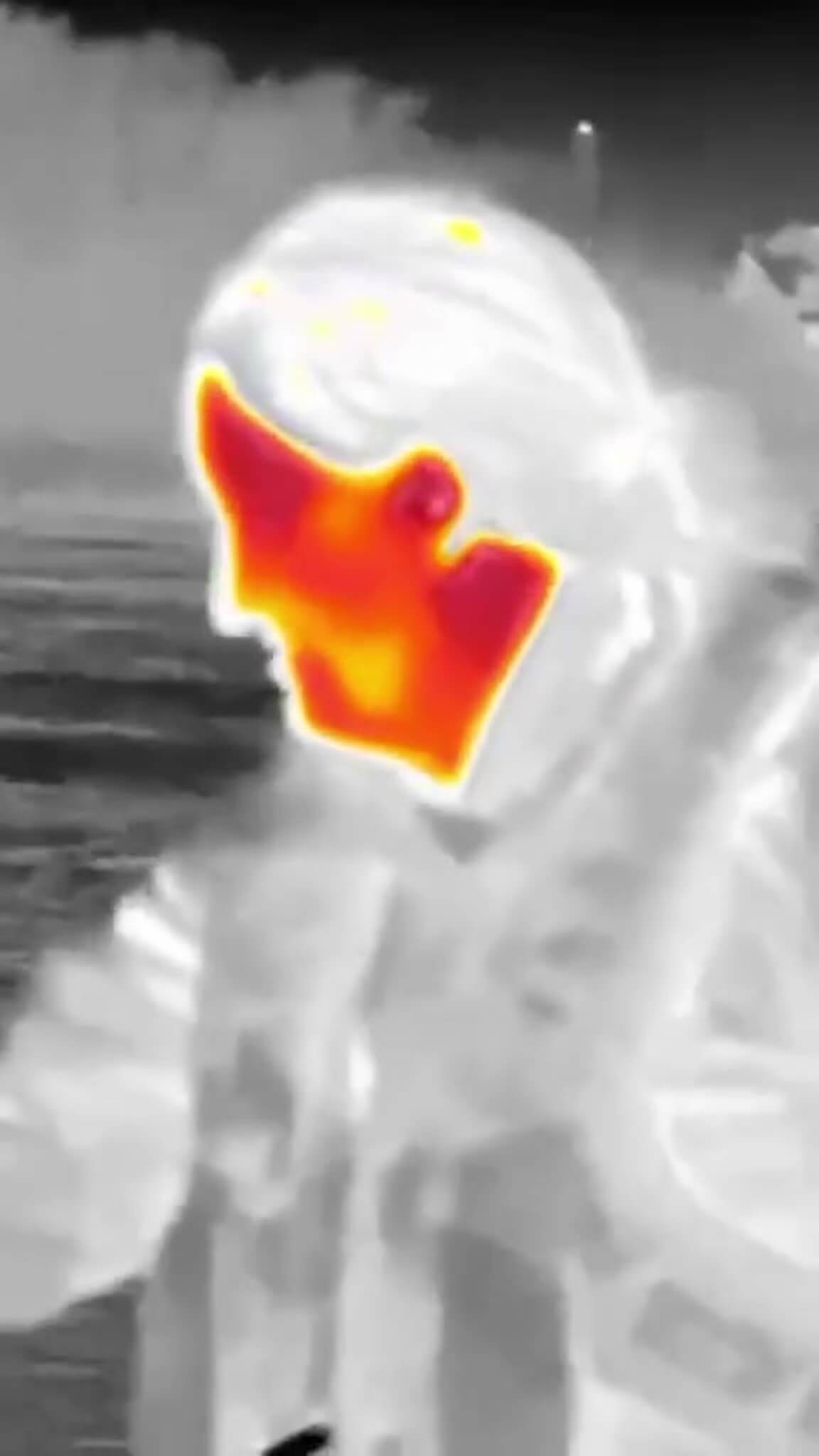 RNLI crew member in full kit seen through a thermal imaging camera, face glowing orange and red