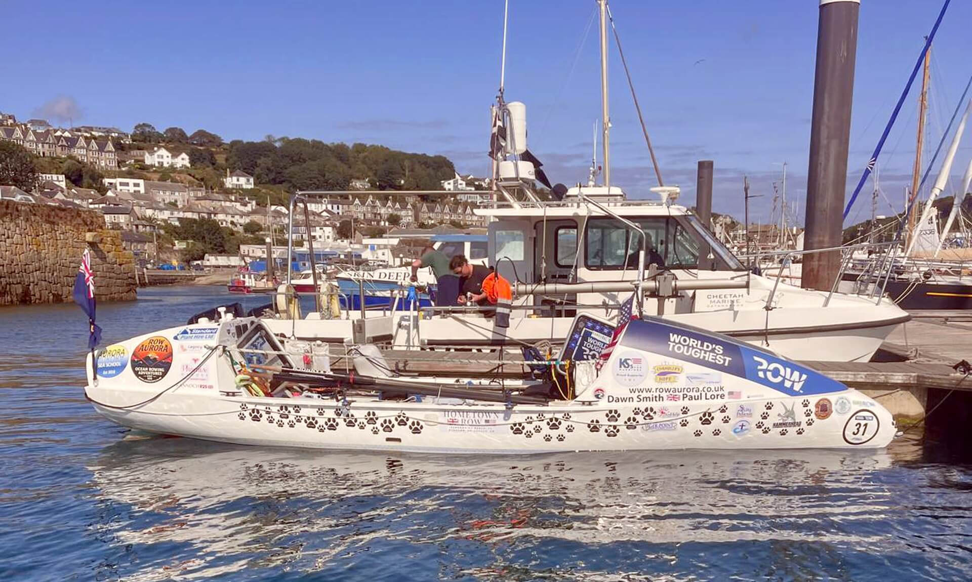 The rowing boat Row Aurora docked in Newlyn harbour on a sunny morning
