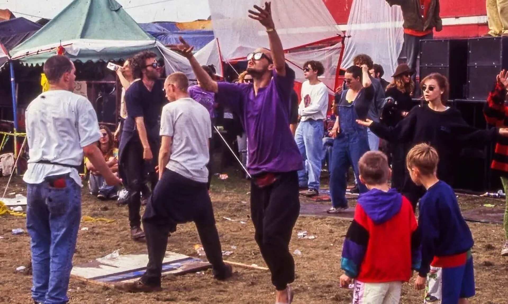 Dancers at an outdoor free party with tents and a double-decker sound-system bus