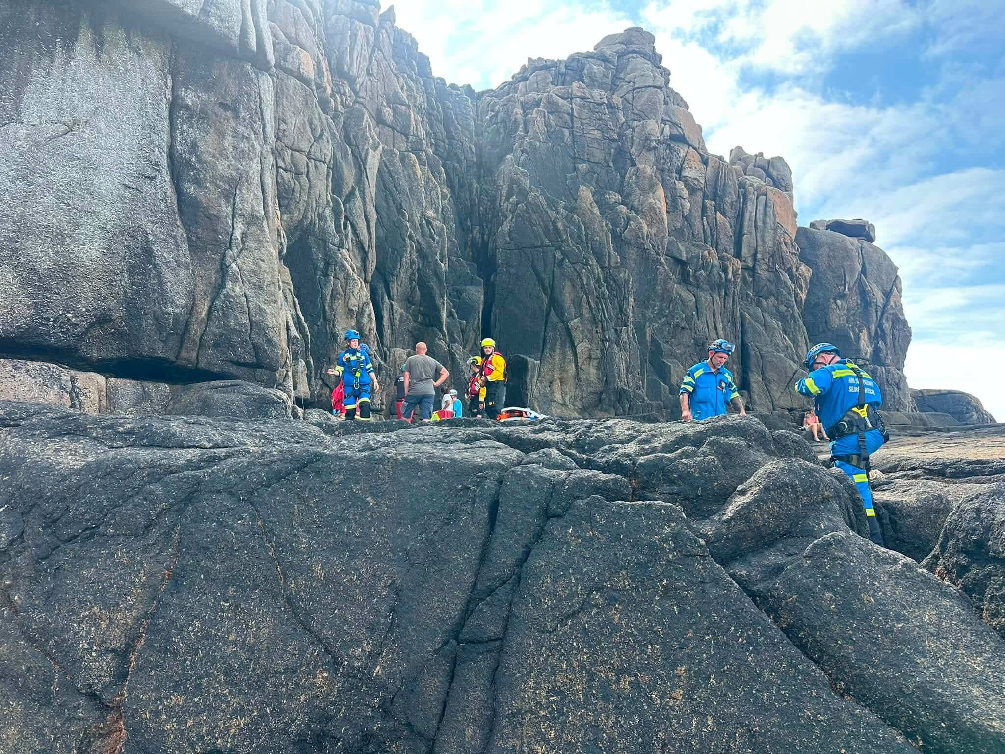 Coastguard and ambulance crews at the base of a granite cliff near Sennen Cove