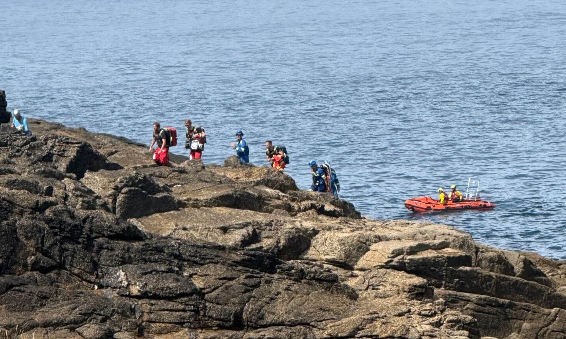 Emergency service crews on rocks at Pedn-men-du with an RNLI inshore lifeboat waiting offshore