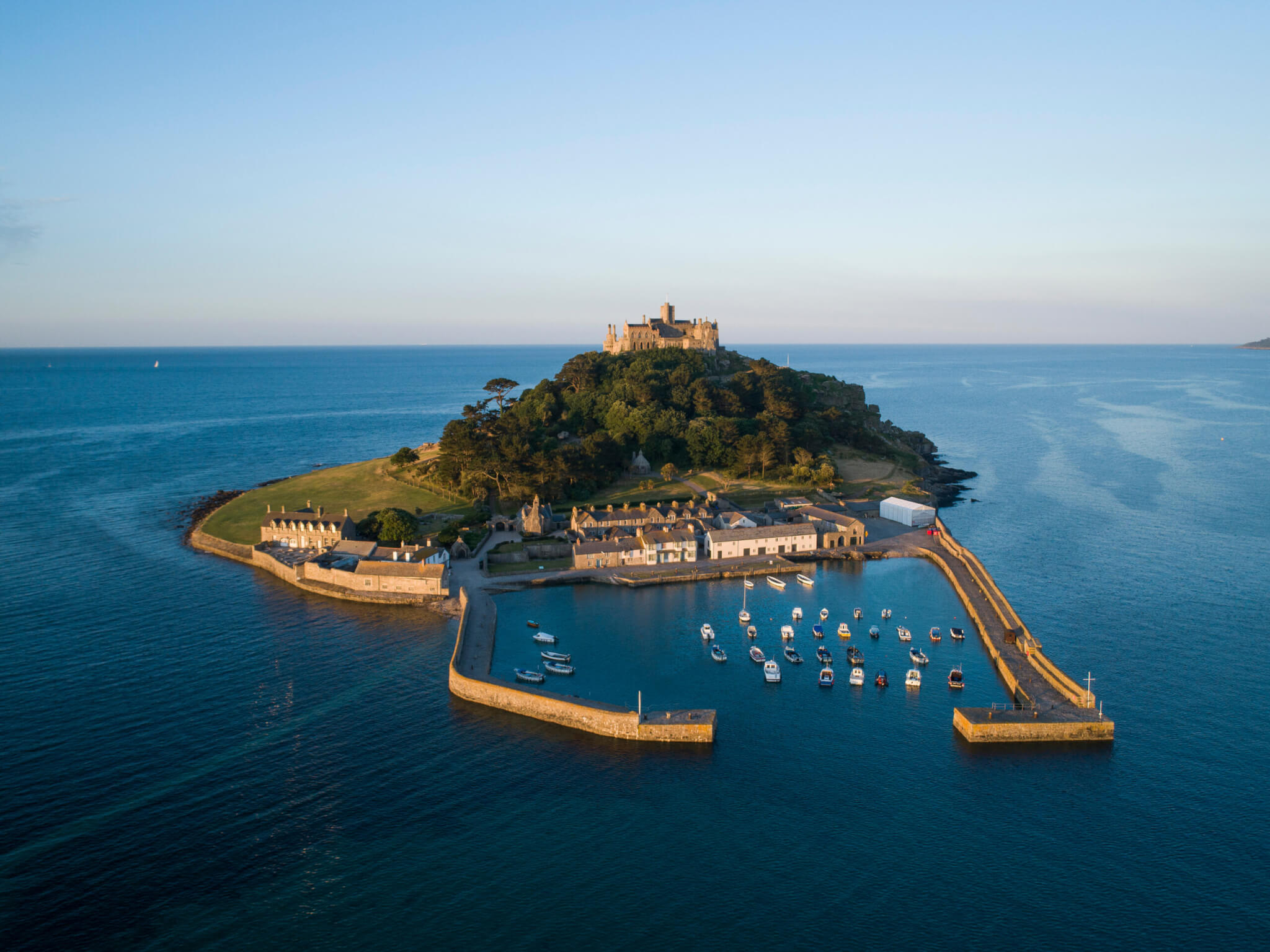 Aerial view of St Michael's Mount, its harbour village and moored boats at sunset