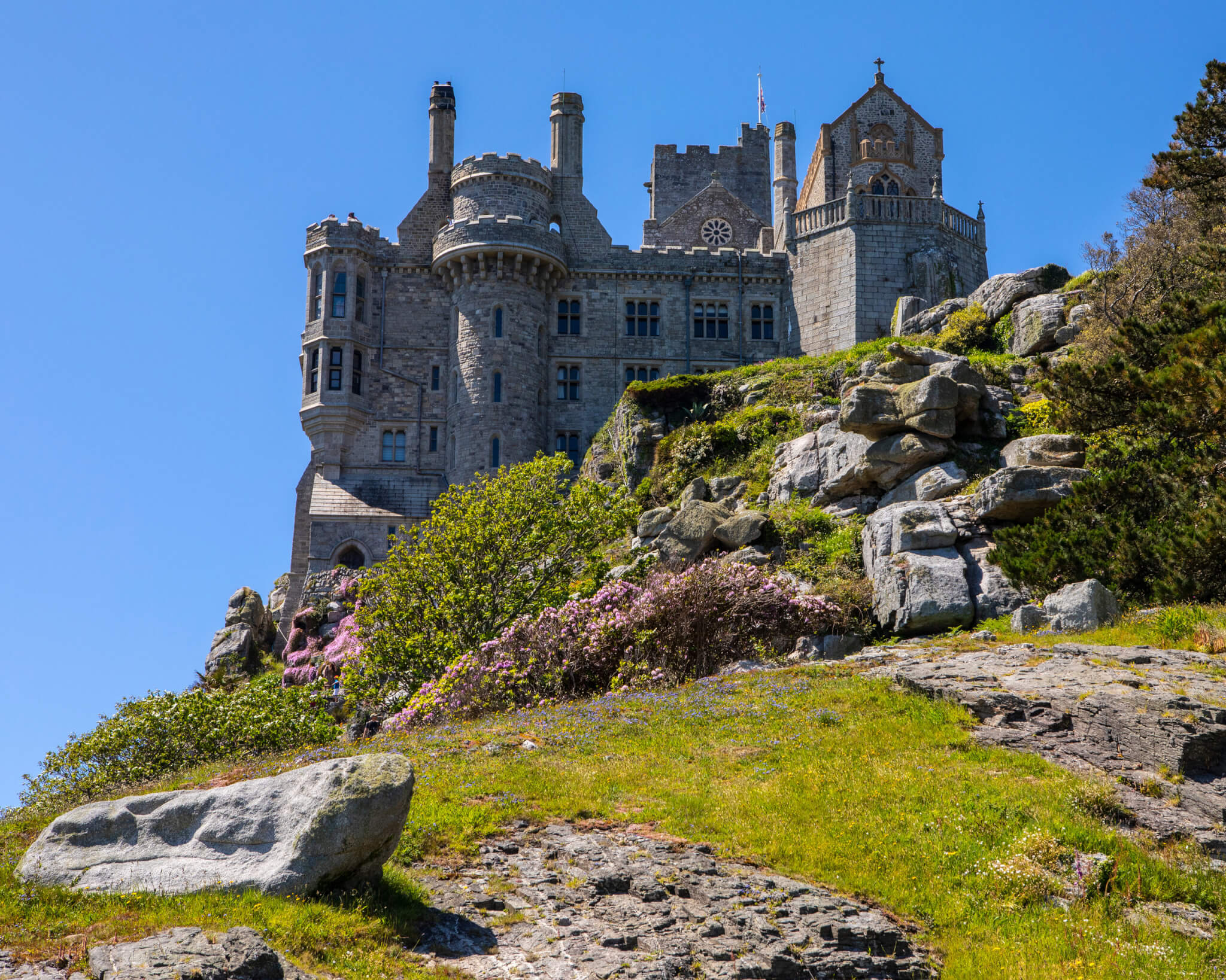 St Michael's Mount castle above granite rocks and flowering shrubs