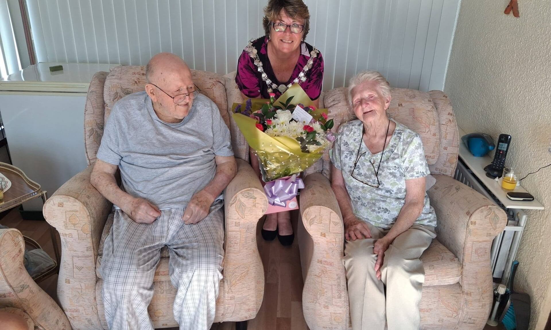 Torpoint's Town Mayor sits between Brian and Joan Jones with an anniversary bouquet