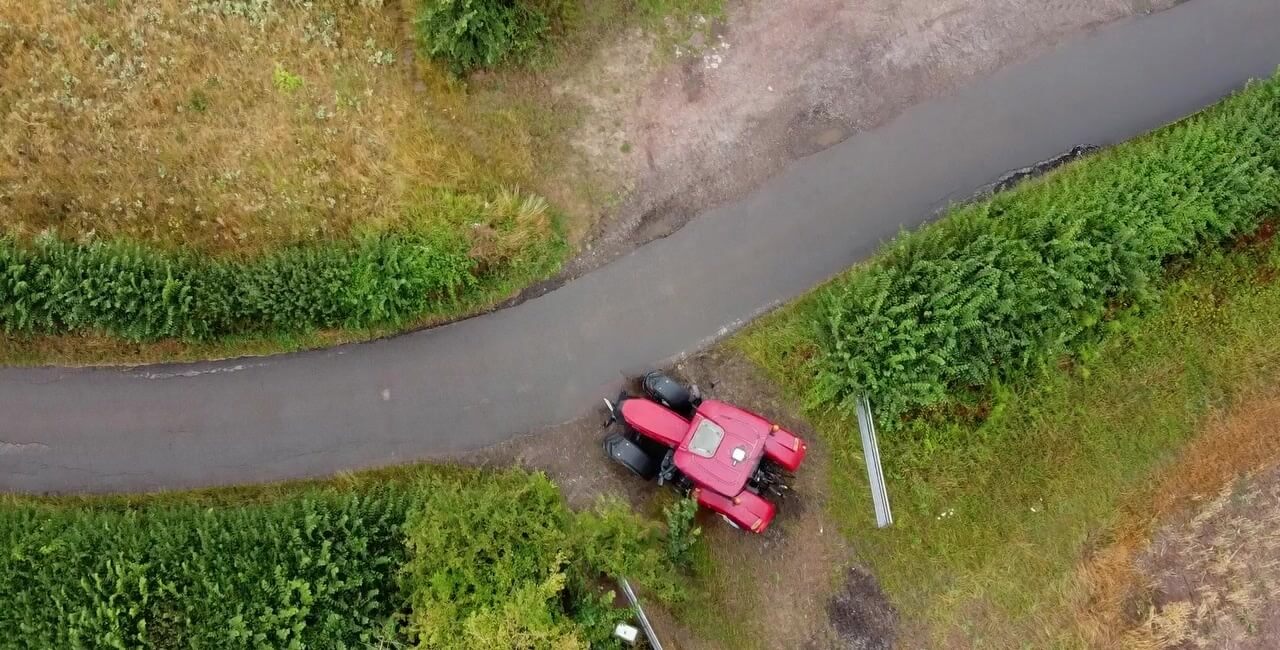 Aerial view of a tractor at a hedge-lined gateway on a Cornish country lane