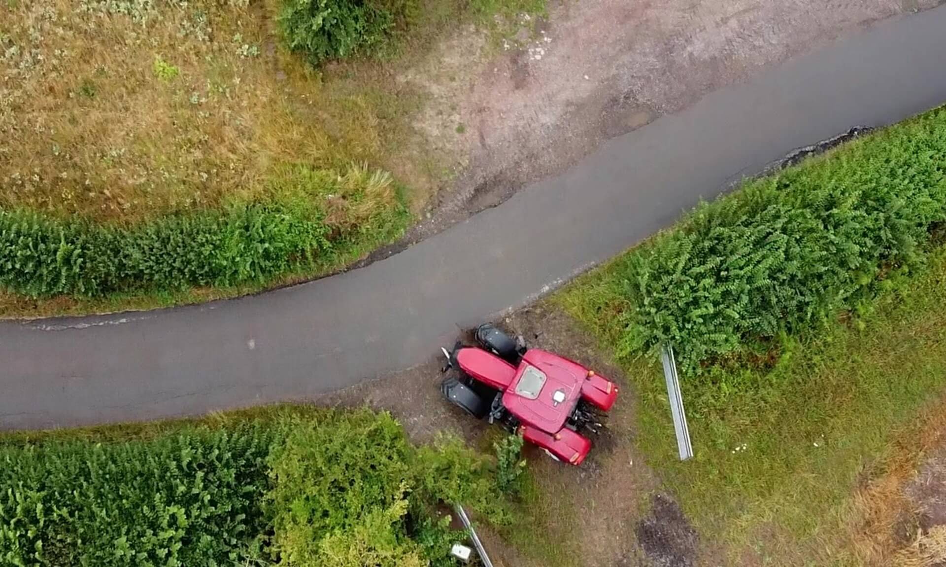 Aerial view of a tractor at a hedge-lined gateway on a Cornish country lane