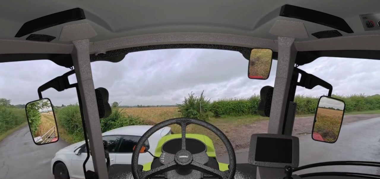 View from inside a tractor cab as a car approaches on a country lane