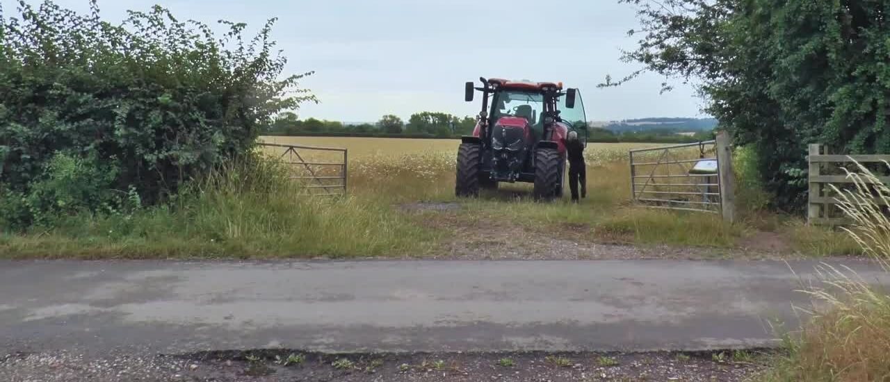 Tractor exiting a field through a concealed hedge-lined gateway
