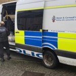 Devon and Cornwall Police van with officers at the rear during a warrant operation