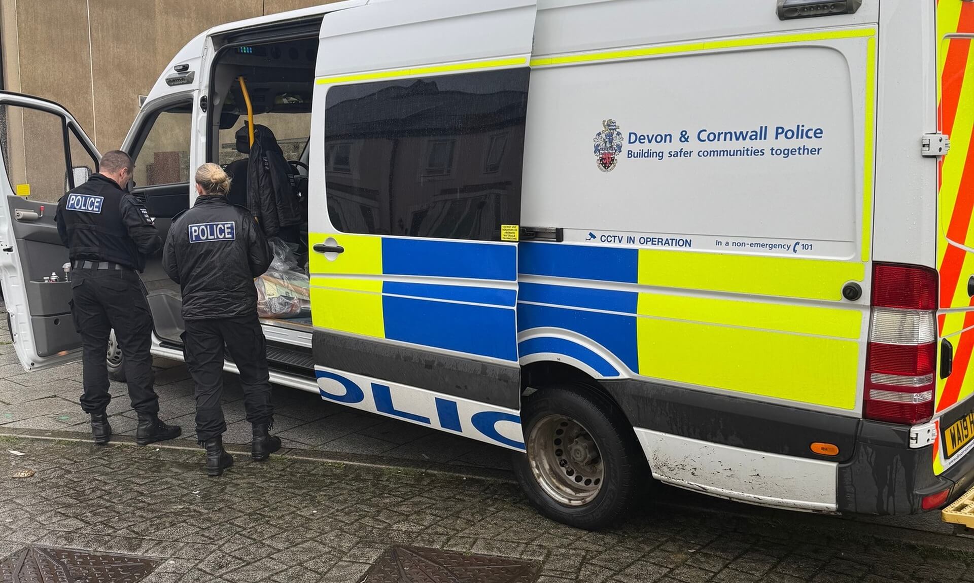 Devon and Cornwall Police van with officers at the rear during a warrant operation