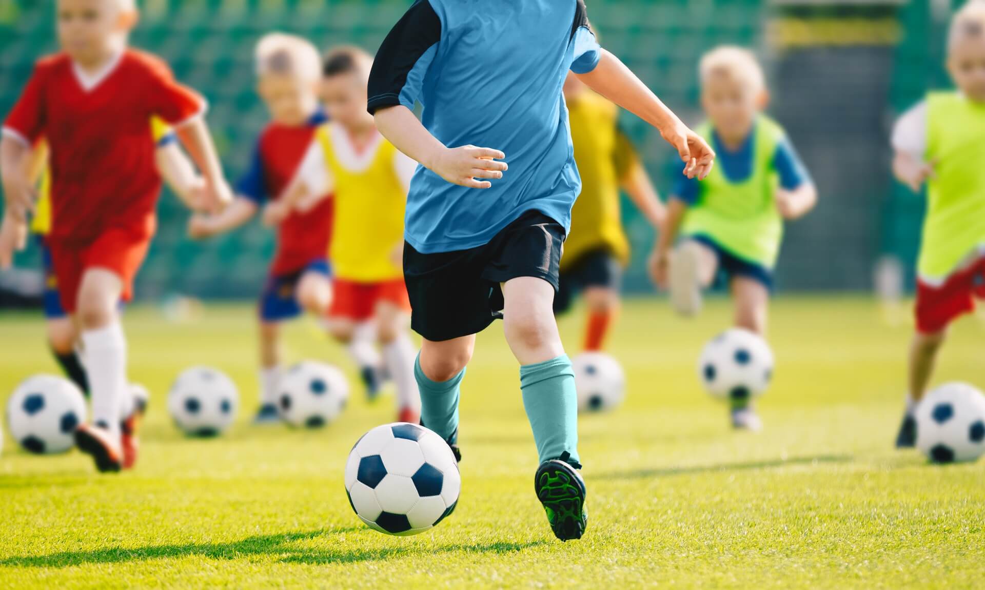 Children playing football on a grass pitch