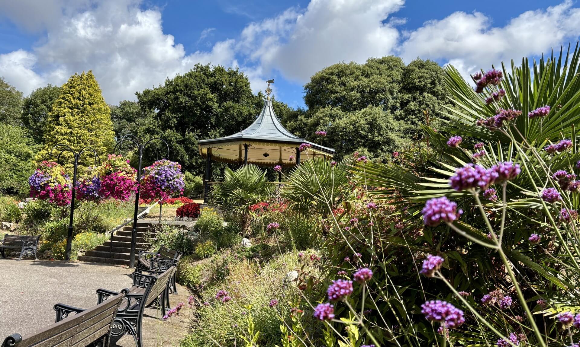 The bandstand at Victoria Gardens, Truro, surrounded by summer floral displays, hanging baskets and palms