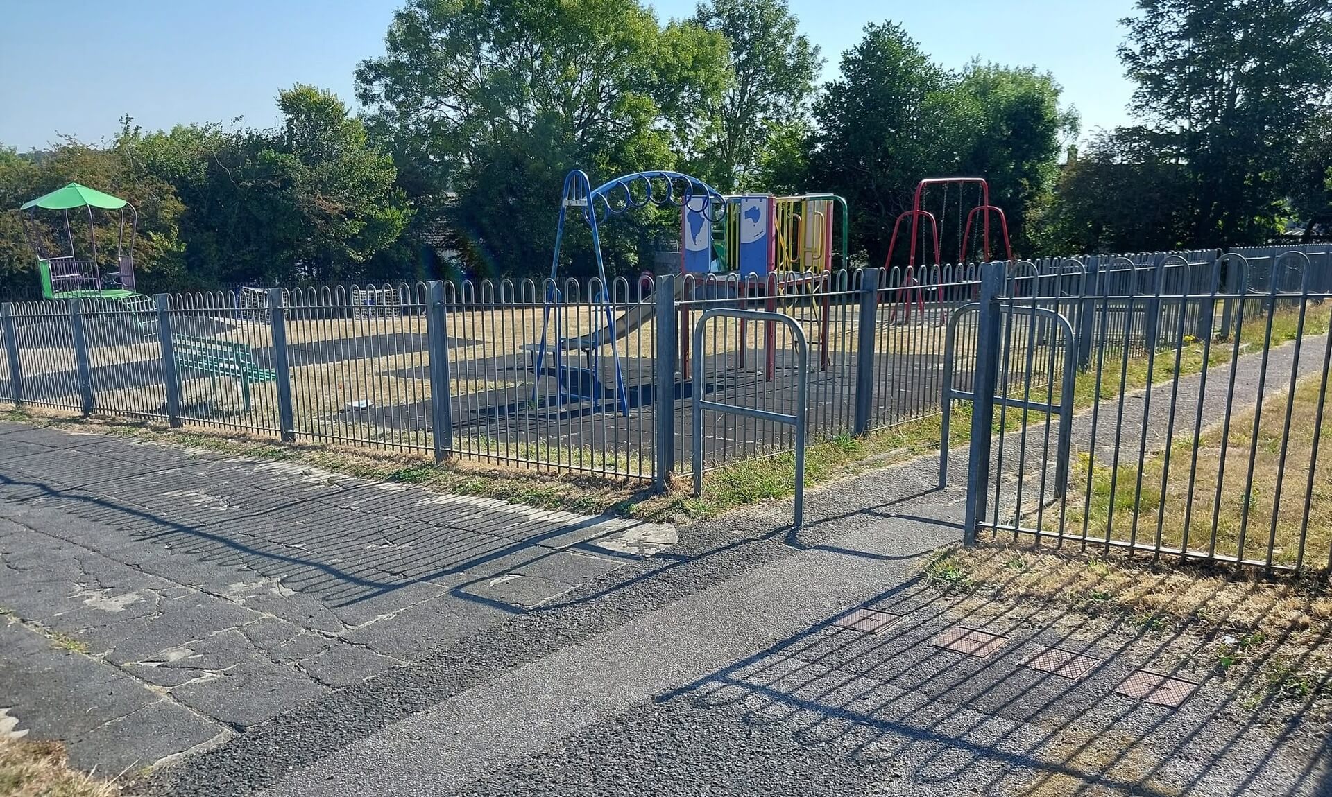 Playground at Behenna Drive park in the Malabar area of Truro, with swings and a climbing frame behind metal railings