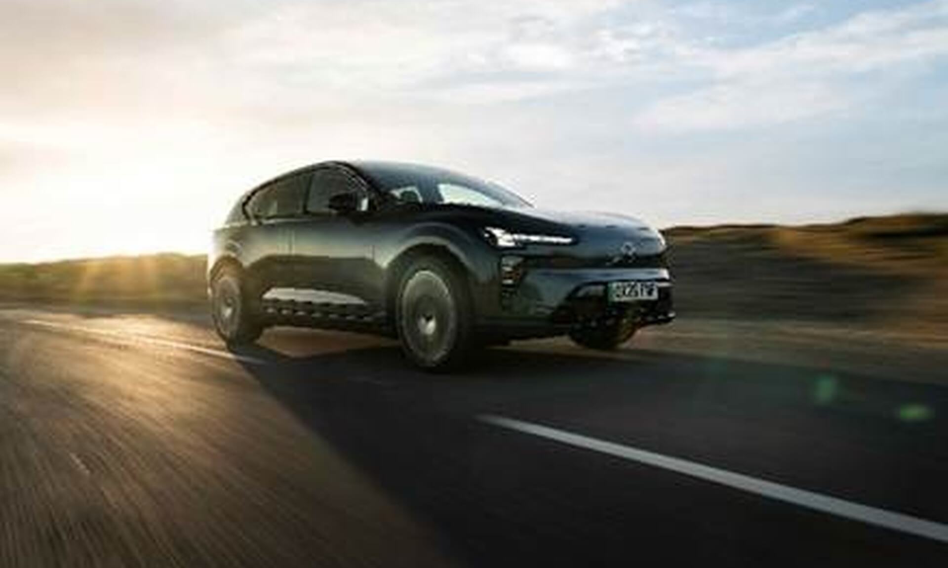 The new Volvo EX60 electric SUV driving on a road at sunset