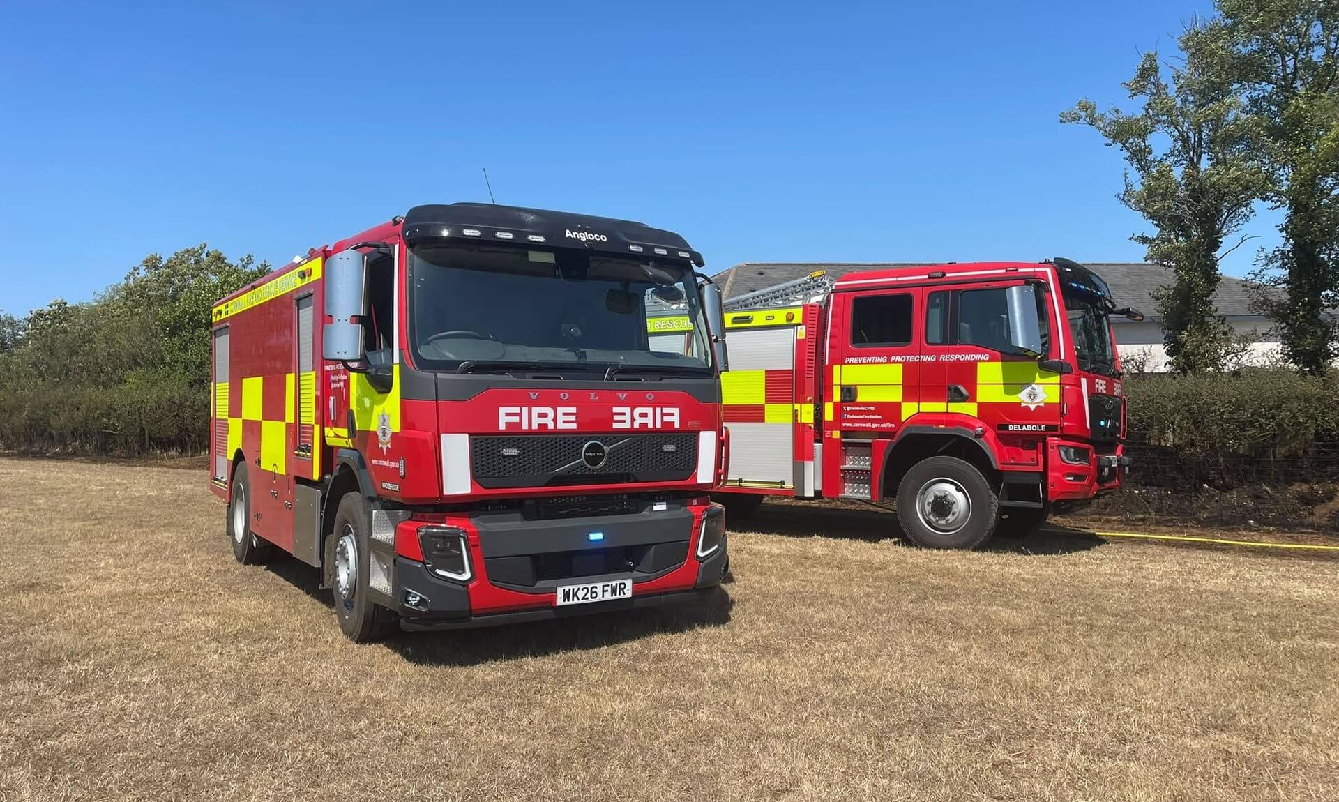Two Cornwall Fire and Rescue Service appliances in a dry field under a clear sky