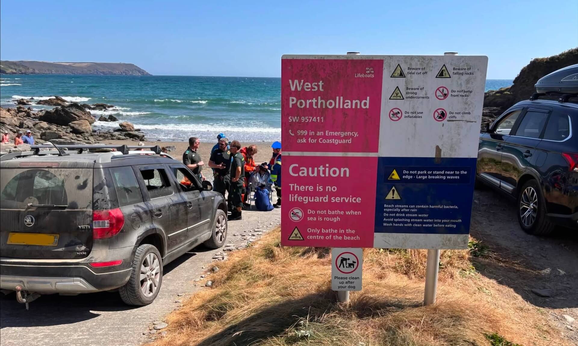Emergency crews on the beach beside the West Portholland safety sign