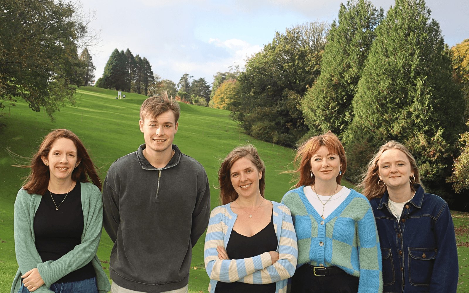 The Oh So Social team of five standing together on grass