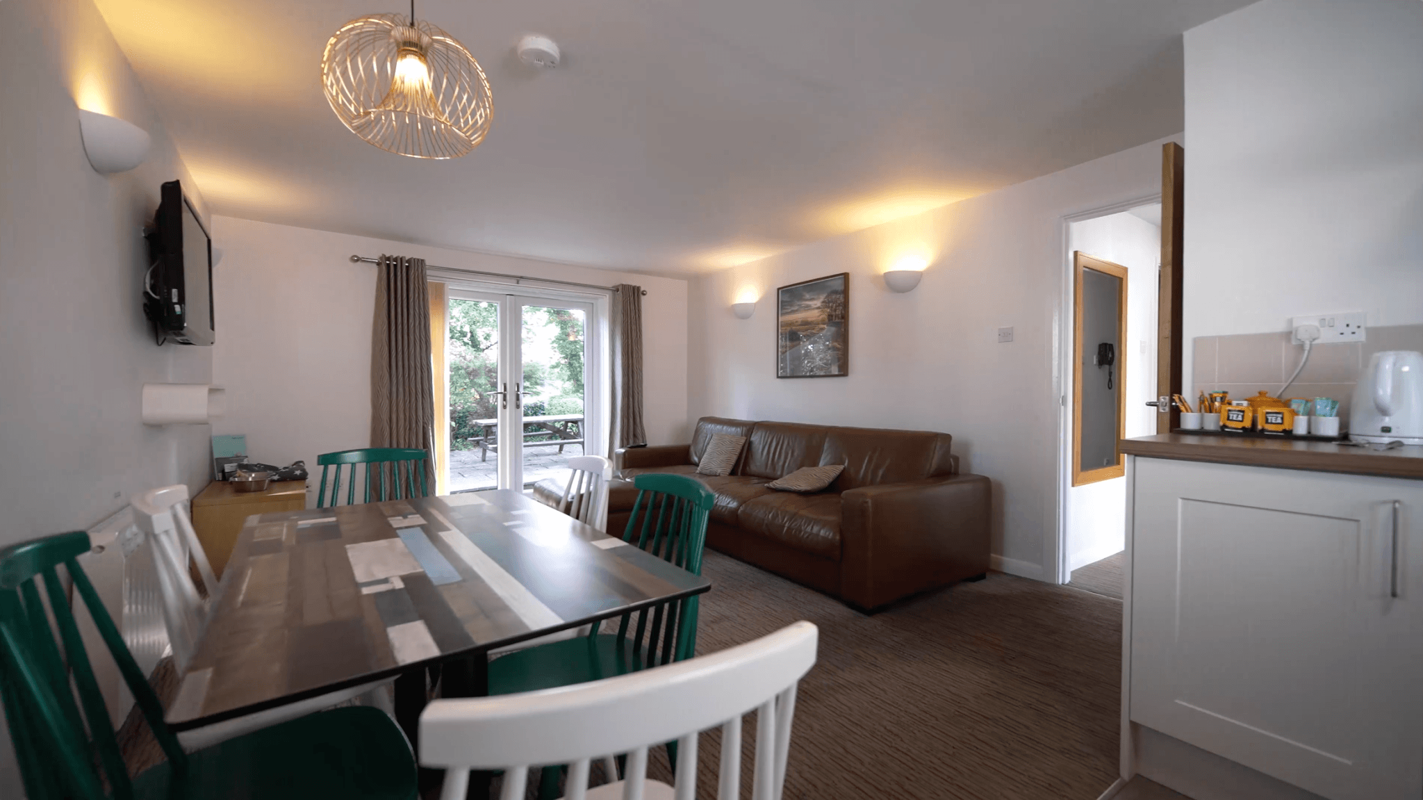 Open-plan lounge and dining area inside a China Fleet Country Club self-catering apartment, with French doors onto a patio