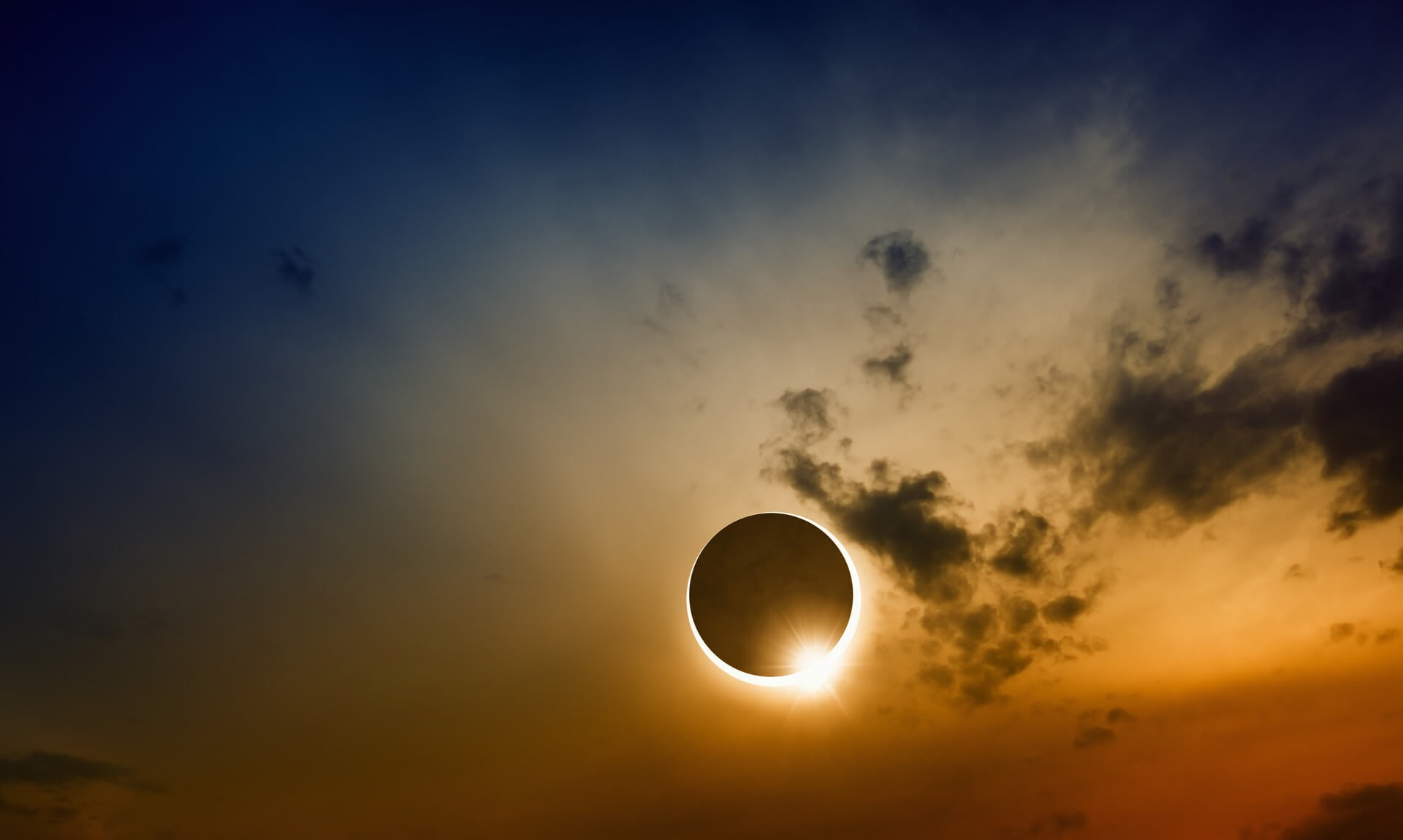 Ring of light around a partial solar eclipse in a cloudy sunset sky