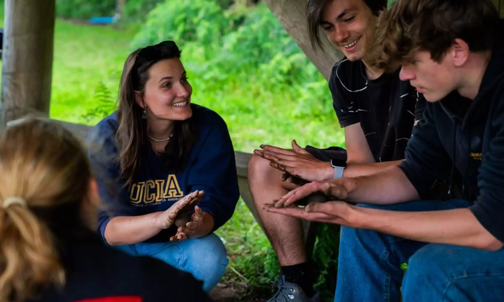 Young people sitting together with muddy hands during a nature activity at the Eden Project