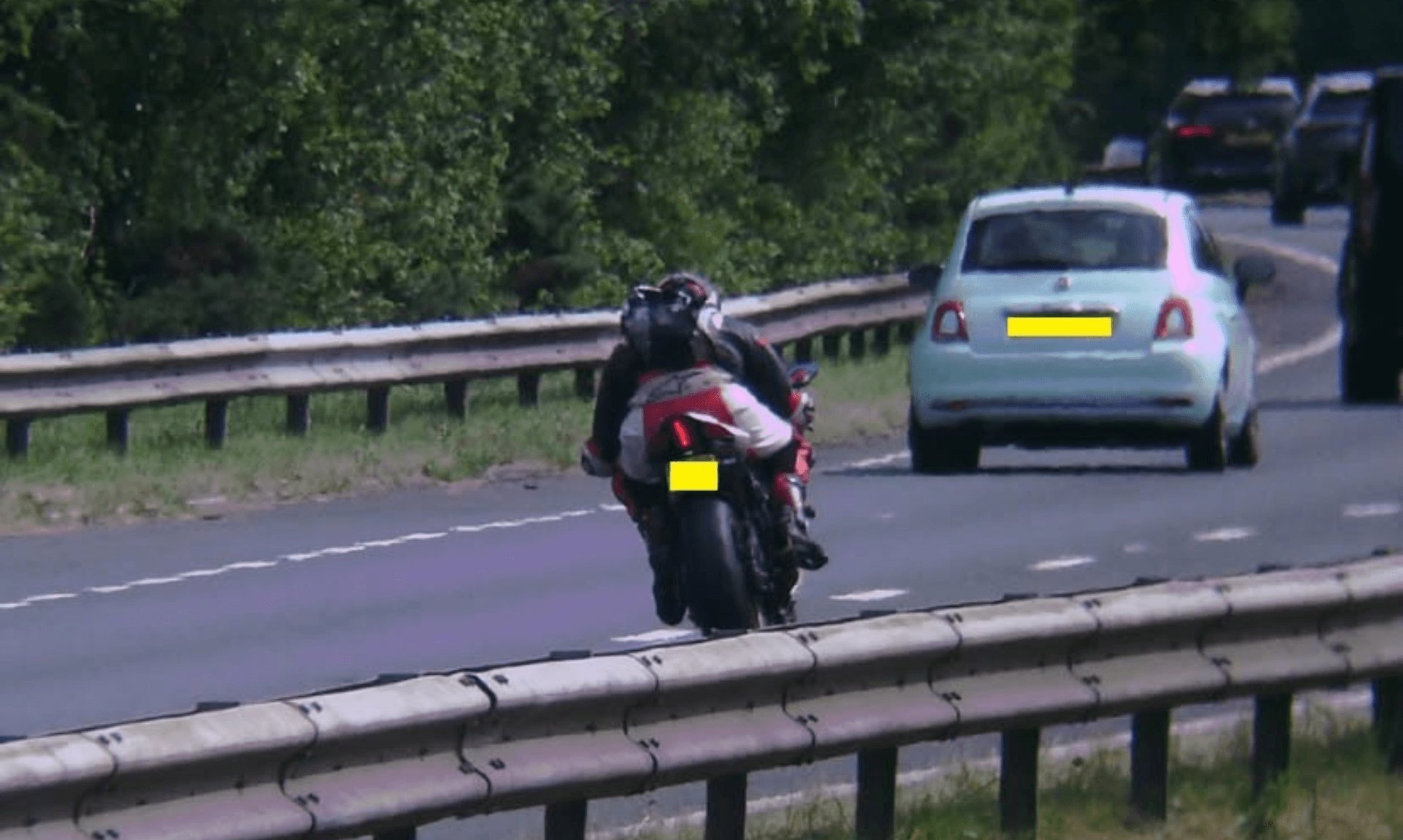 Motorcyclist riding a red sports bike past a light blue Fiat 500 on the A30 near Bodmin