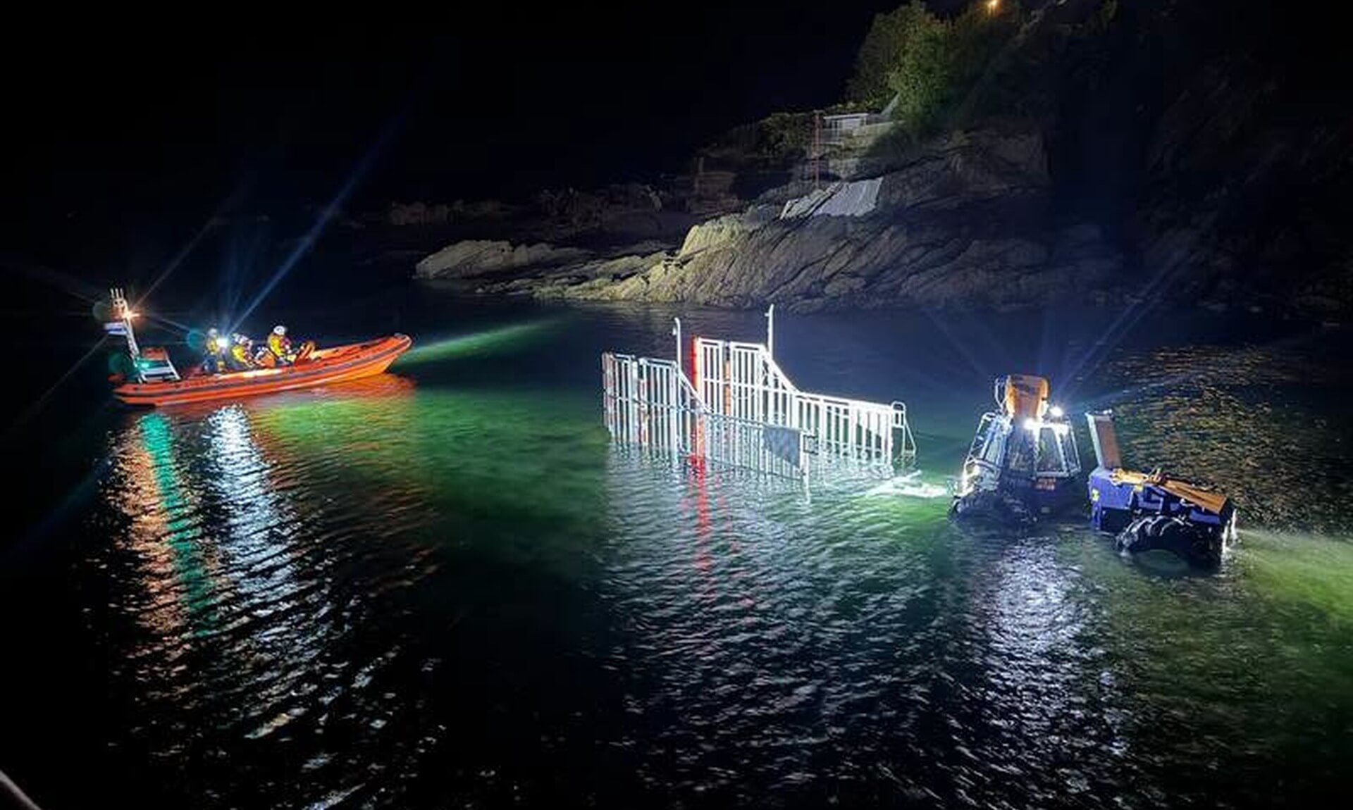 RNLI Looe lifeboats being recovered at night beside the rocks