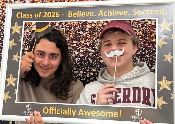 Two Treviglas Academy students posing with props in the Class of 2026 photo frame