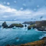 Rain-specked view over a Cornish cove and cliffs