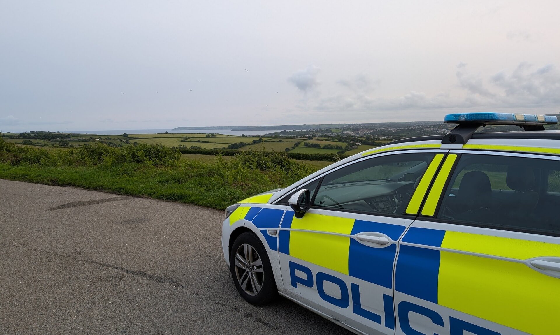 Devon and Cornwall Police car parked overlooking St Austell Bay