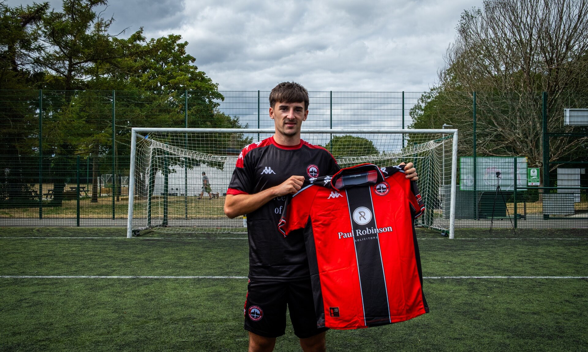 Tom Dean holding the Truro City home shirt on the pitch after signing on loan