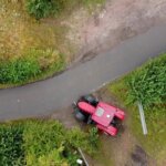Aerial view of a tractor at a hedge-lined gateway on a Cornish country lane