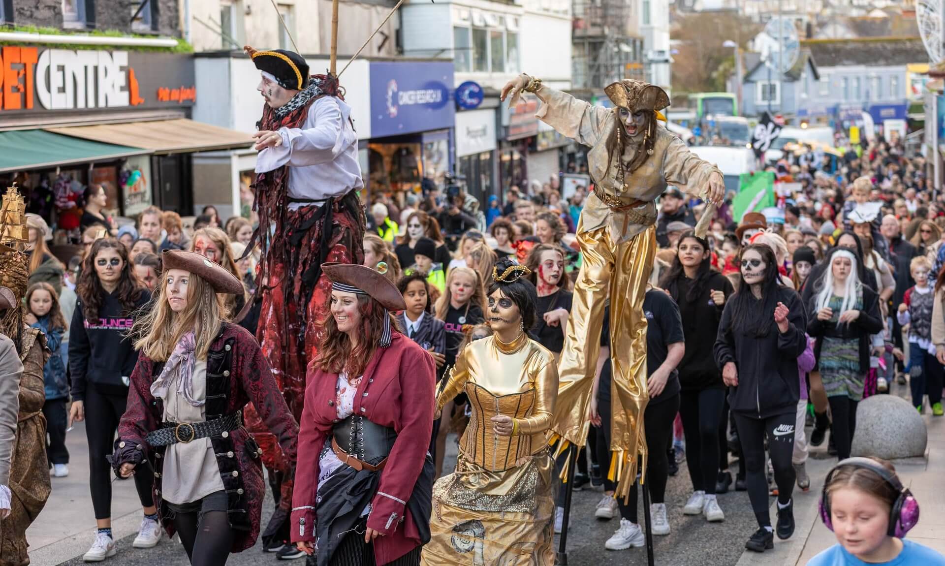 Costumed stilt-walkers and crowds at Newquay's Zombie Crawl