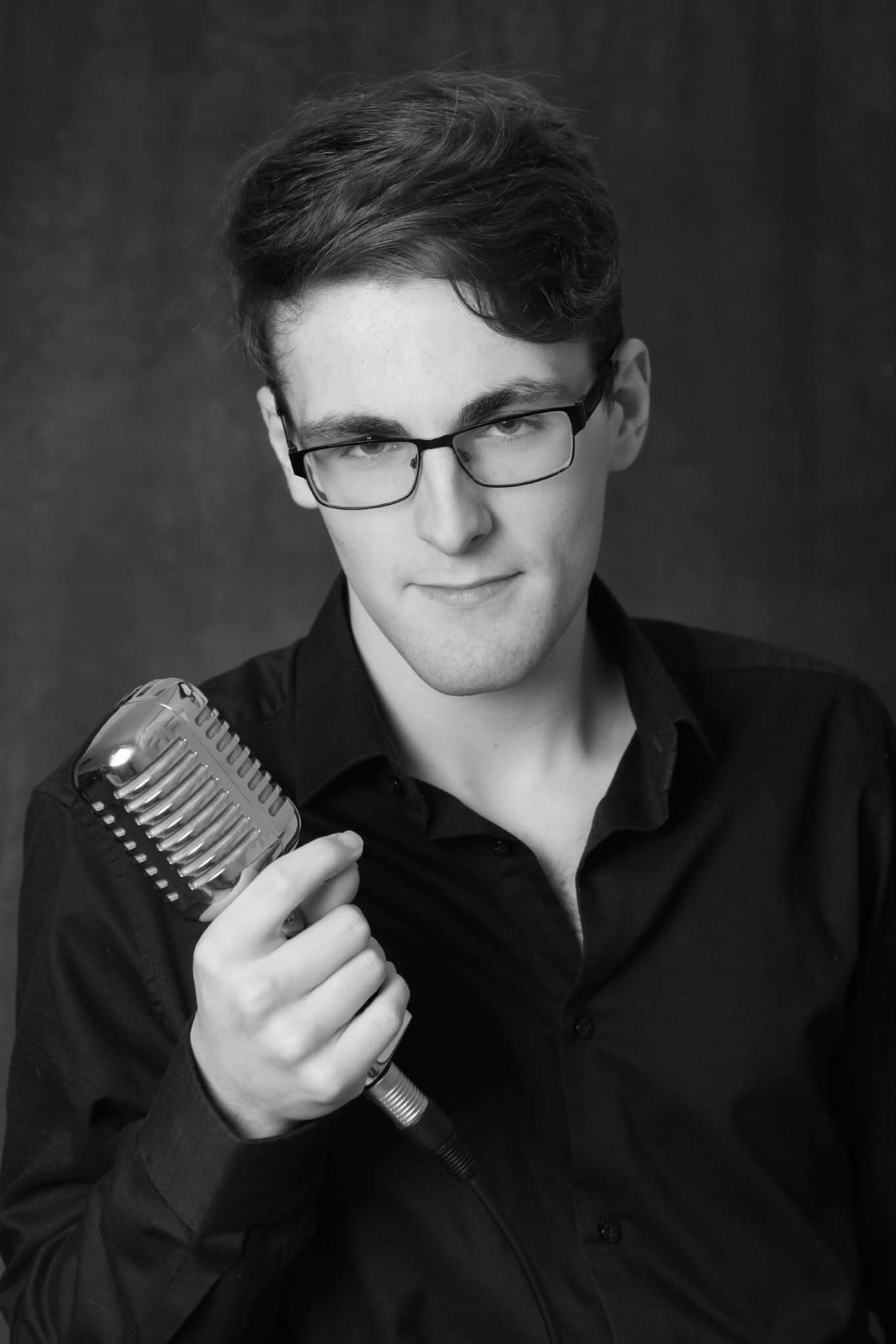 Black and white portrait of Jacob Reed holding a vintage microphone