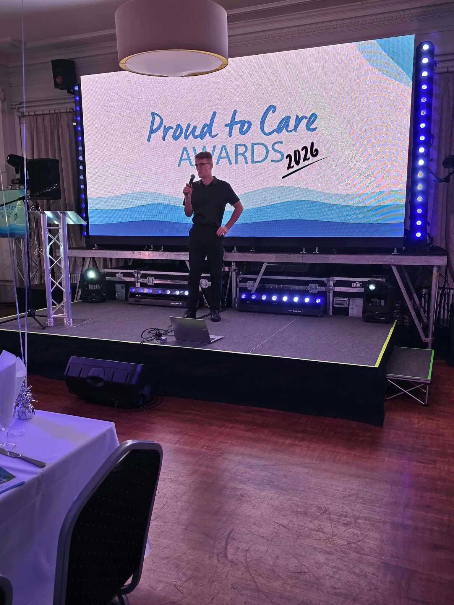 Jacob Reed on stage in front of a Proud to Care Awards 2026 screen