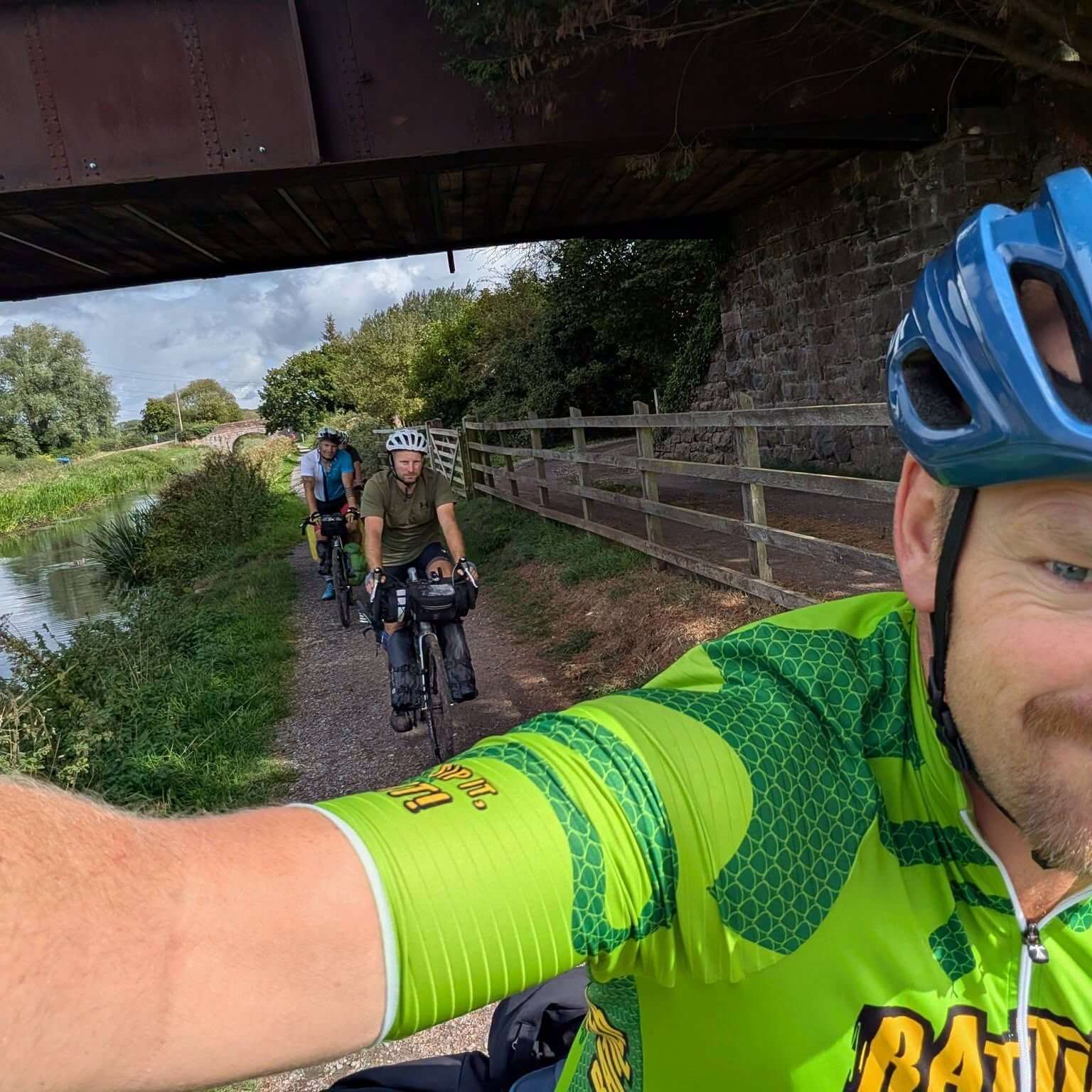 The four riders cycling a canal towpath under a bridge on the way to Land's End