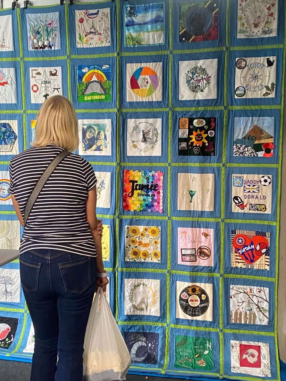 Visitor looking at a blue-bordered Speak Their Name memorial quilt