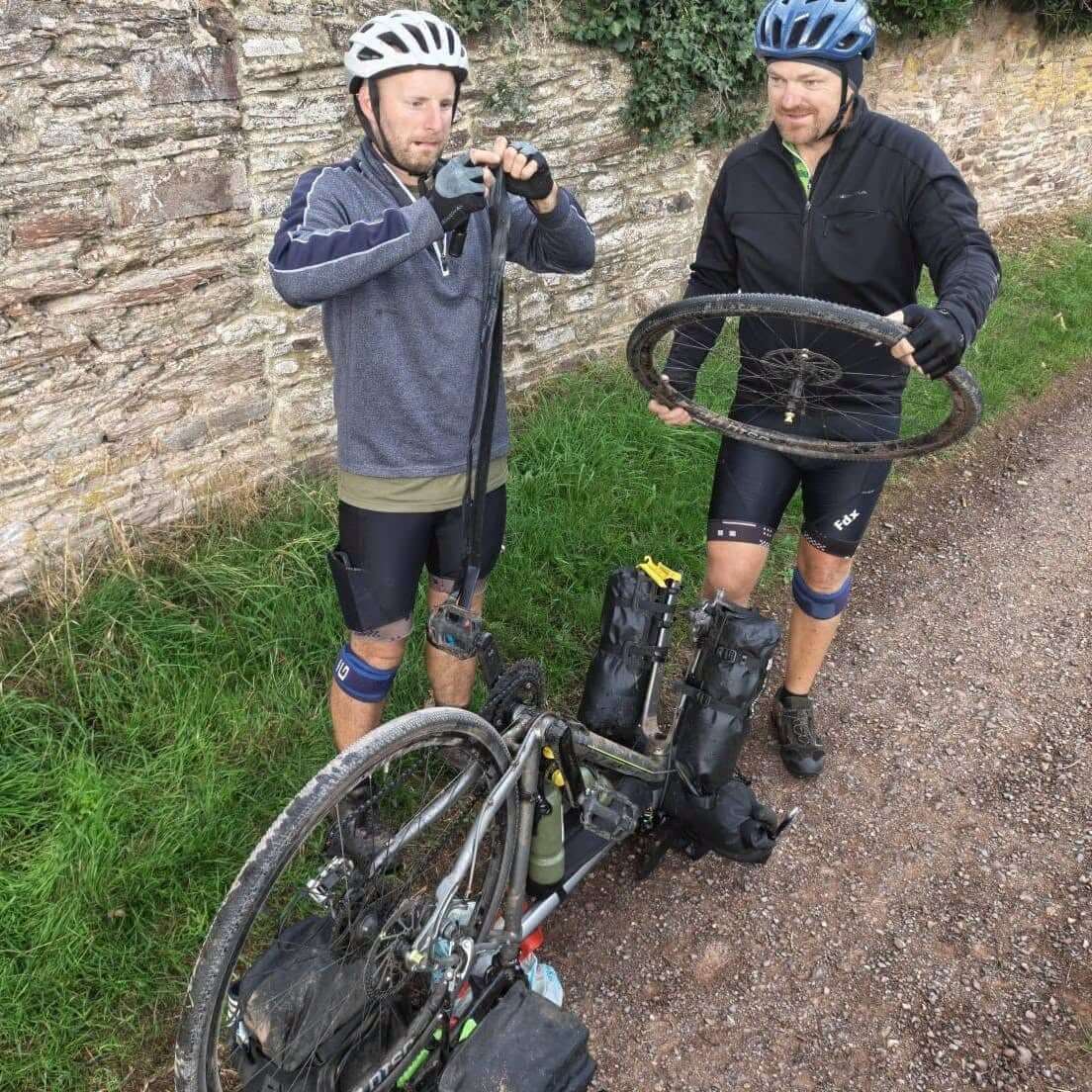 Two of the riders fixing a punctured wheel at the roadside