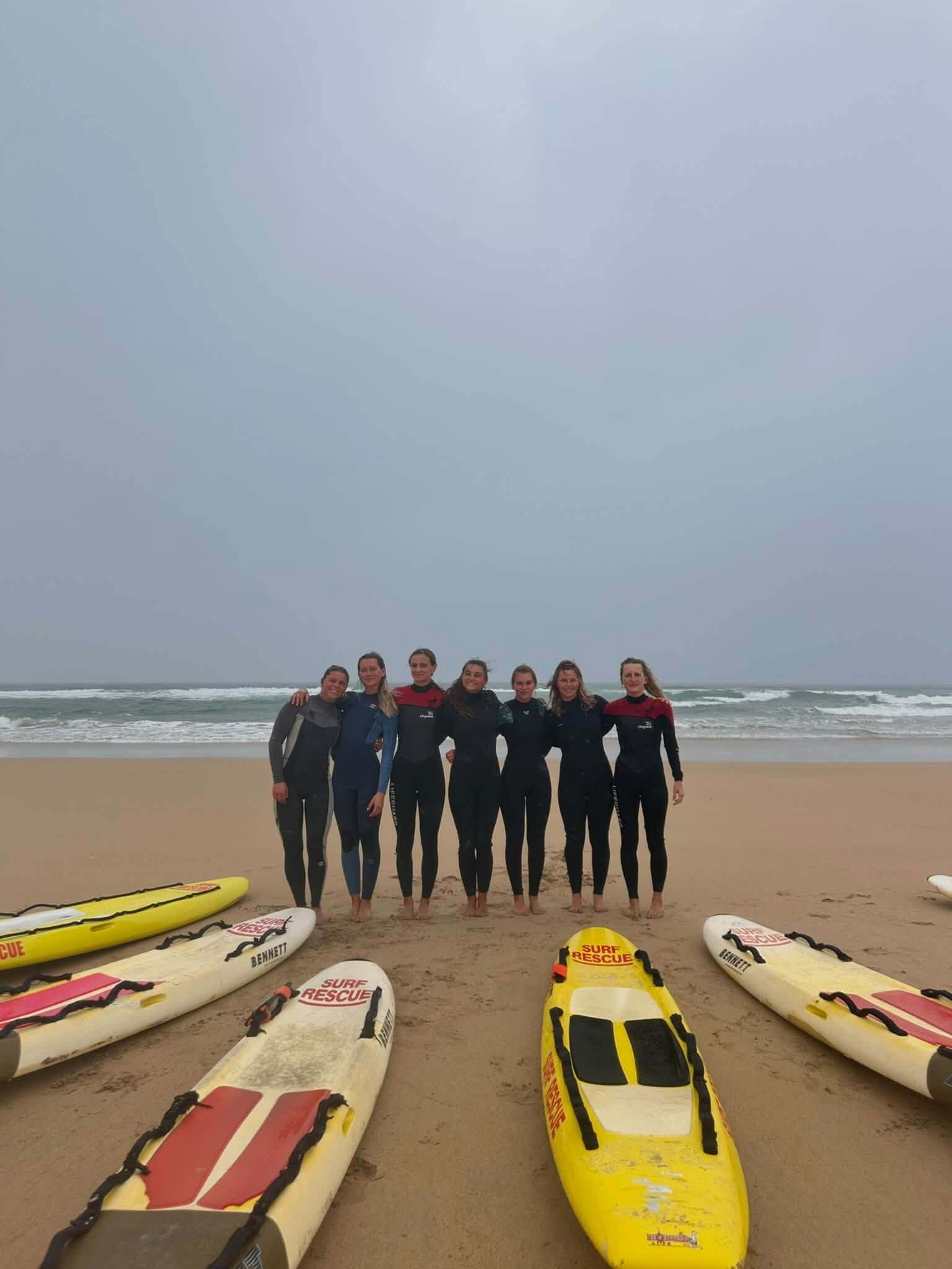 Group of lifeguards in wetsuits on the beach with rescue boards
