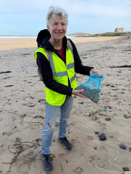 Fistral Beach Clean volunteer holding a tulle bag of material sieved from the strand line on Fistral Beach