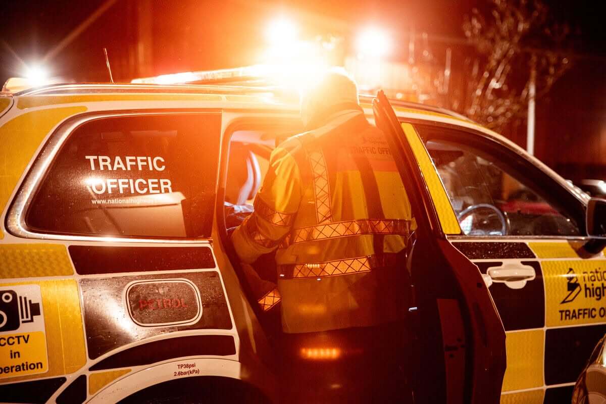 National Highways traffic officer at a patrol vehicle at night