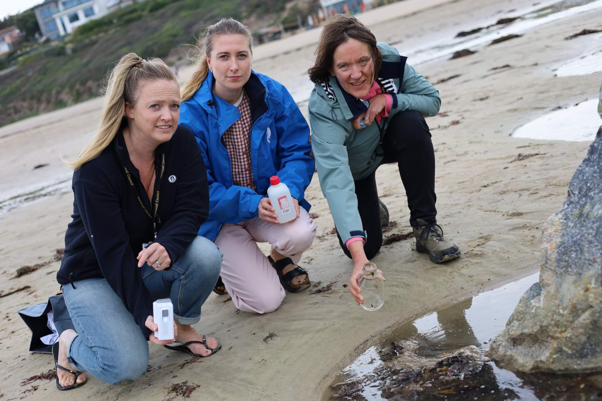 Councillors crouching on the sand taking water samples