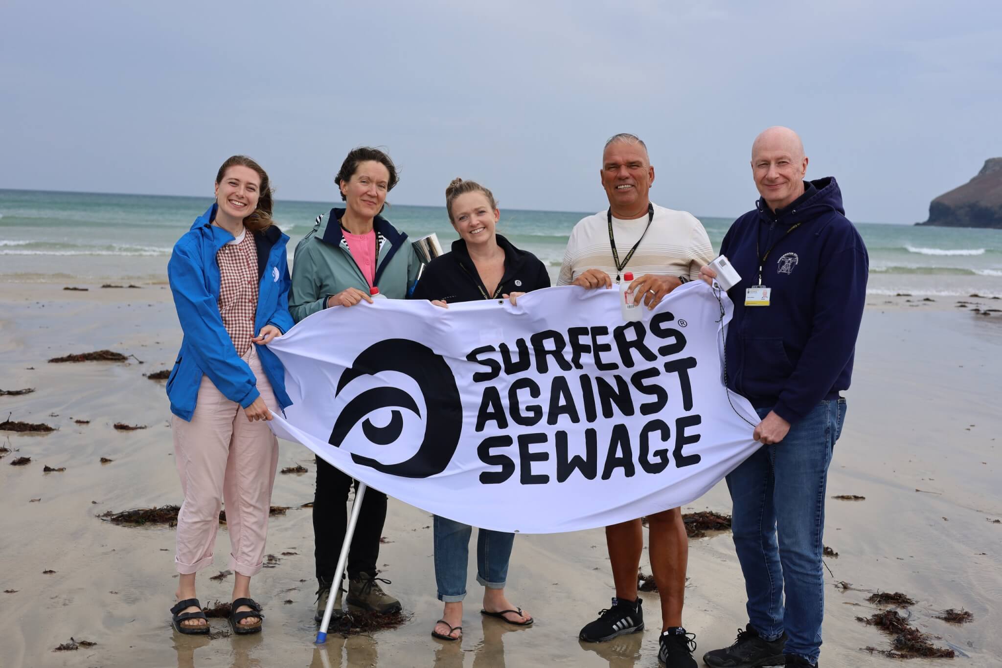 Councillors on the beach holding a Surfers Against Sewage banner