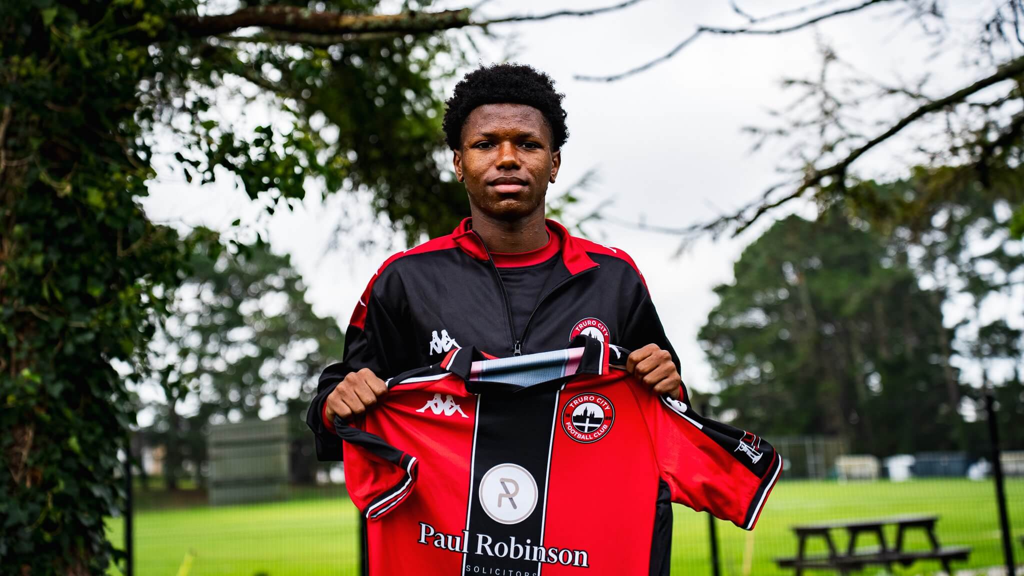 Zyan Blake holding up a Truro City home shirt