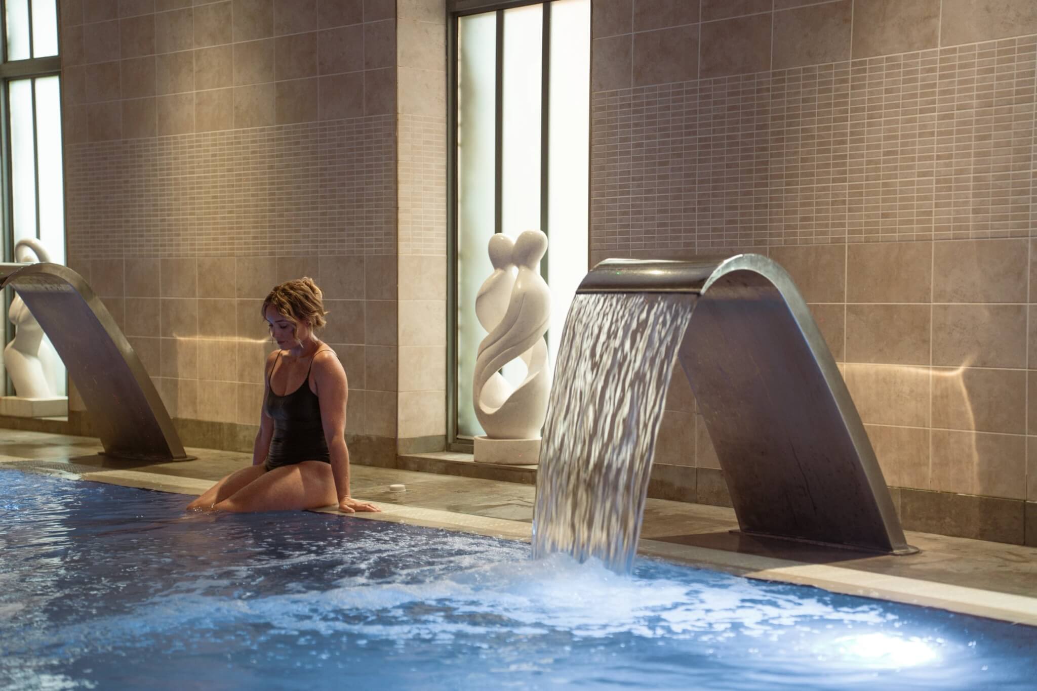 Guest sitting by the vitality pool water feature at Fistral Spa, Newquay